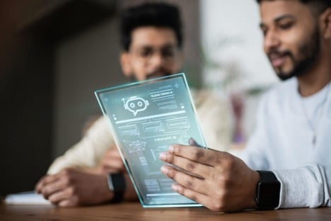 Two people are looking at a transparent tablet with a digital interface displaying diagrams and an icon for AI chatbots for customer service Two people are looking at a transparent tablet with a digital interface displaying diagrams and an icon for AI chatbots for customer service