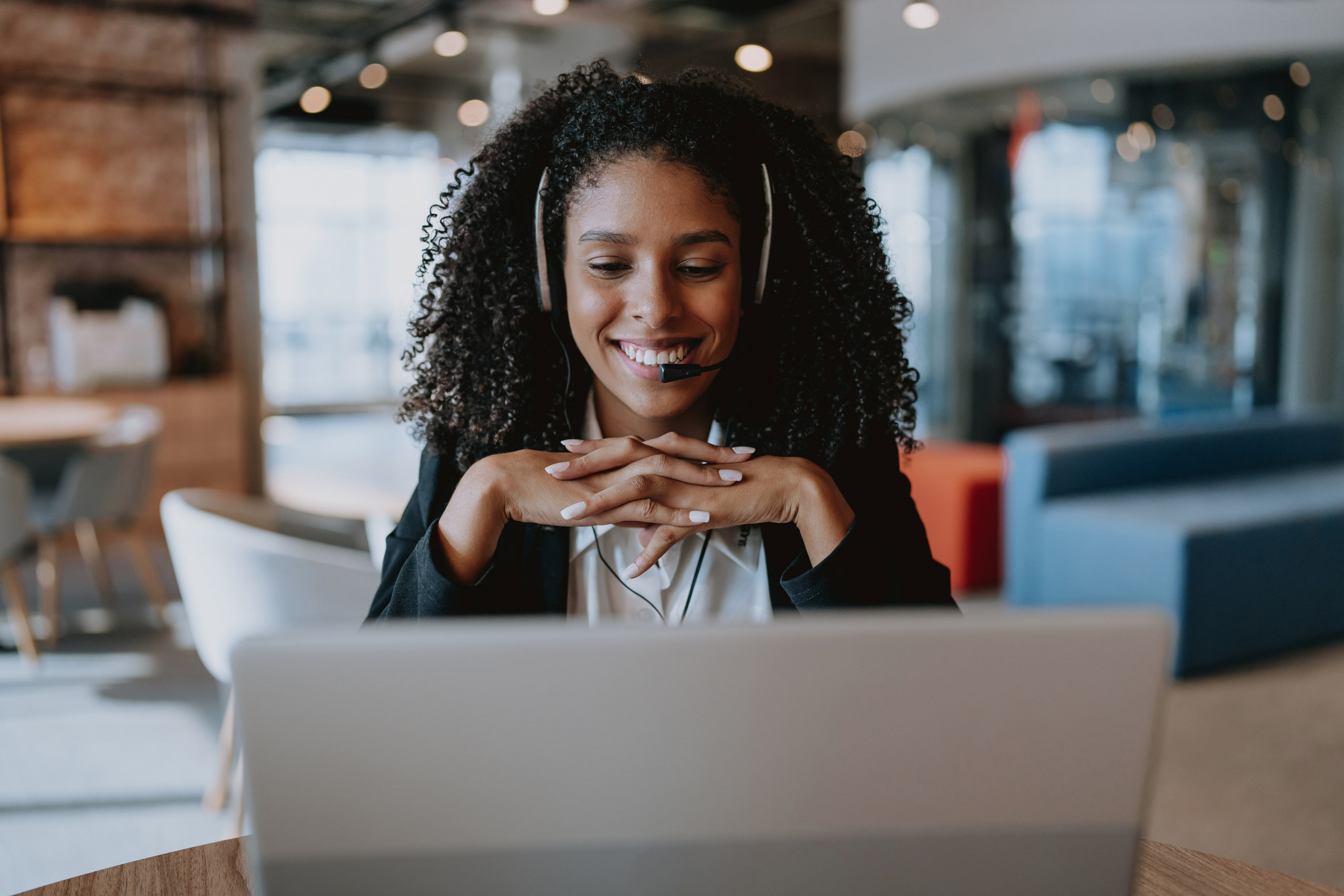 Woman smiles as she speaks on a phone and looks at a computer during a virtual customer experience
