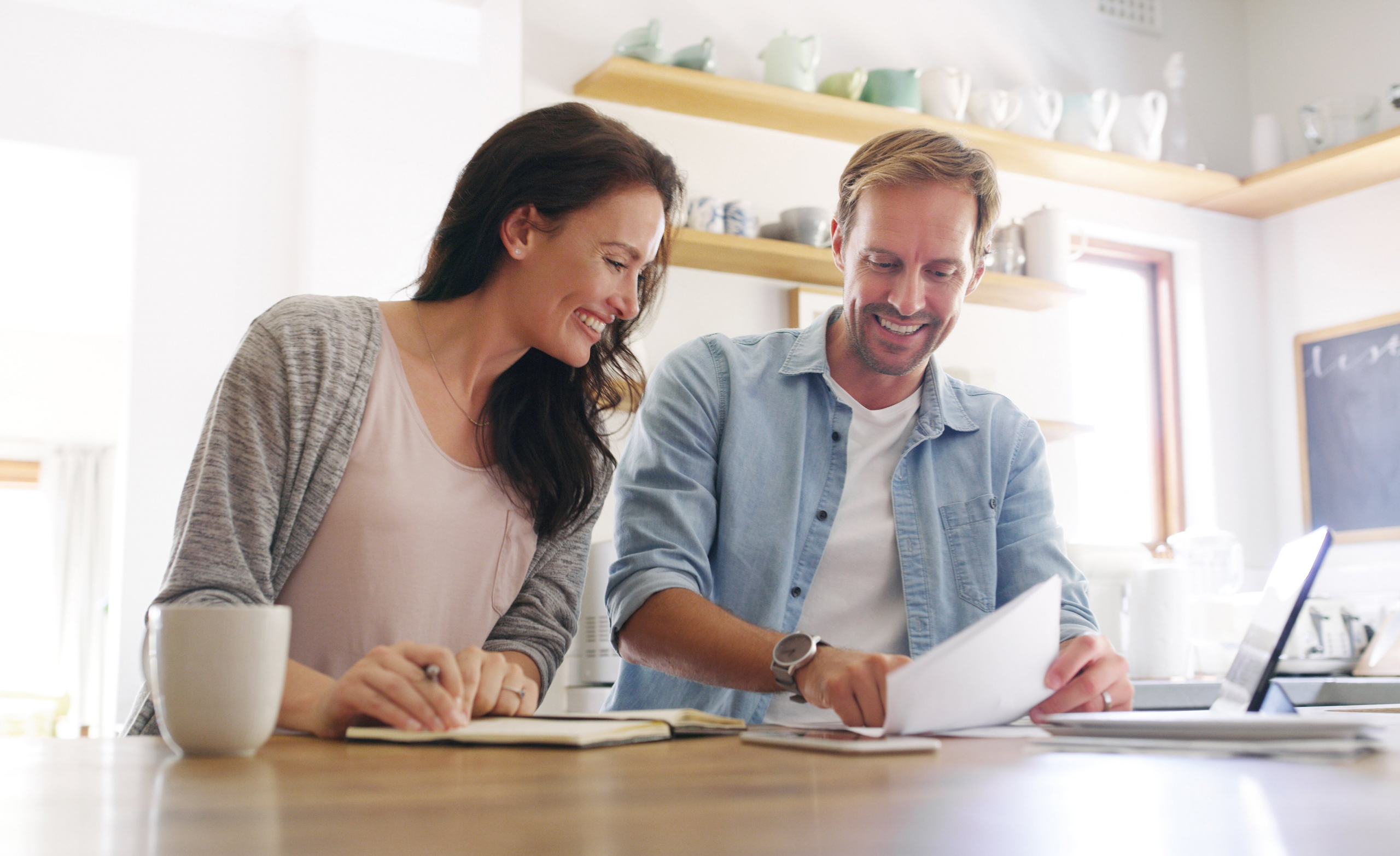 Young happy people looking at paperwork of budget savings.