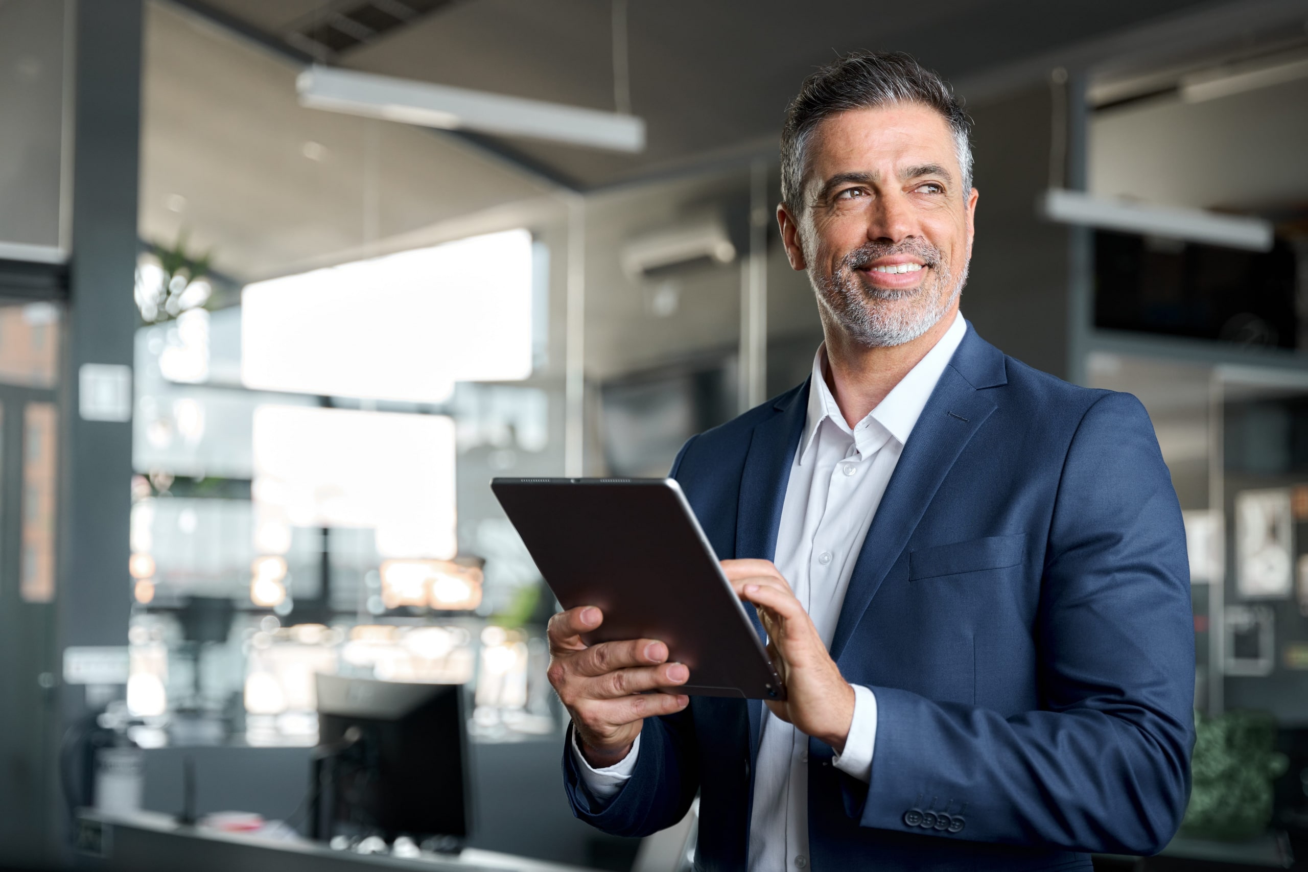 man in suit smiling while using tablet in hands.