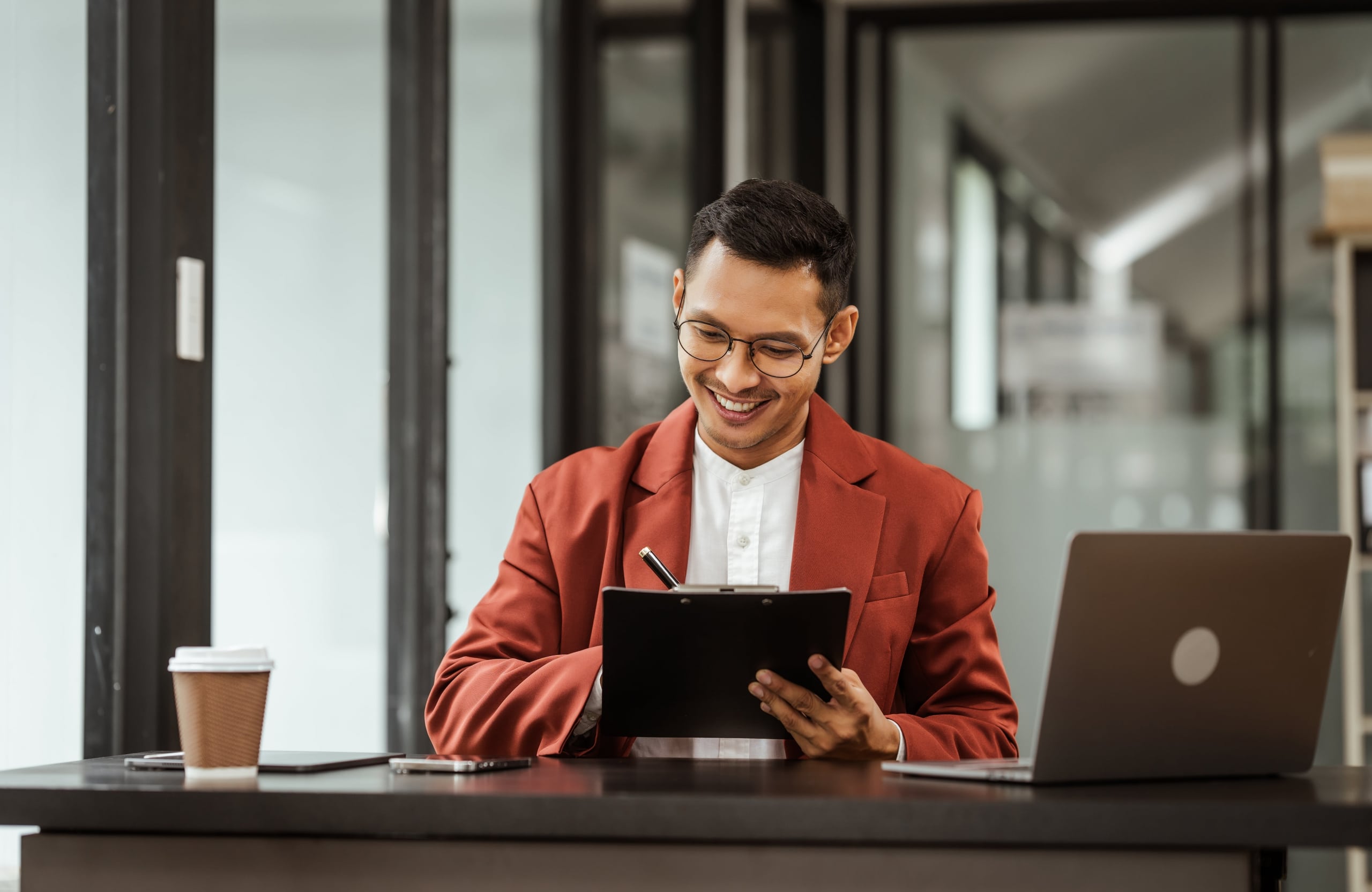 Middle-aged Asian businessman in formal suit working diligently at his desk.