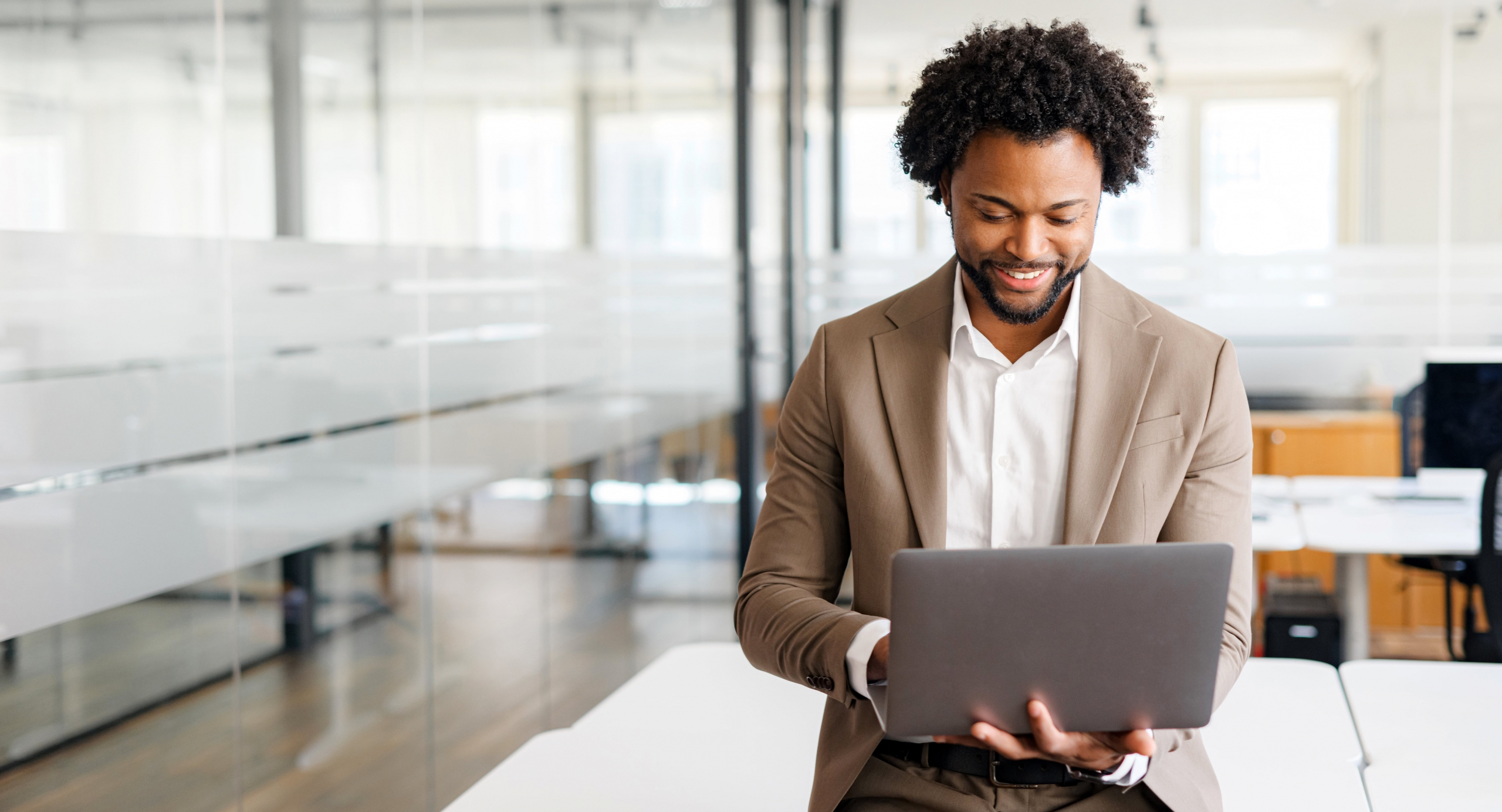 A man with a laptop or similar device in what looks like an office area