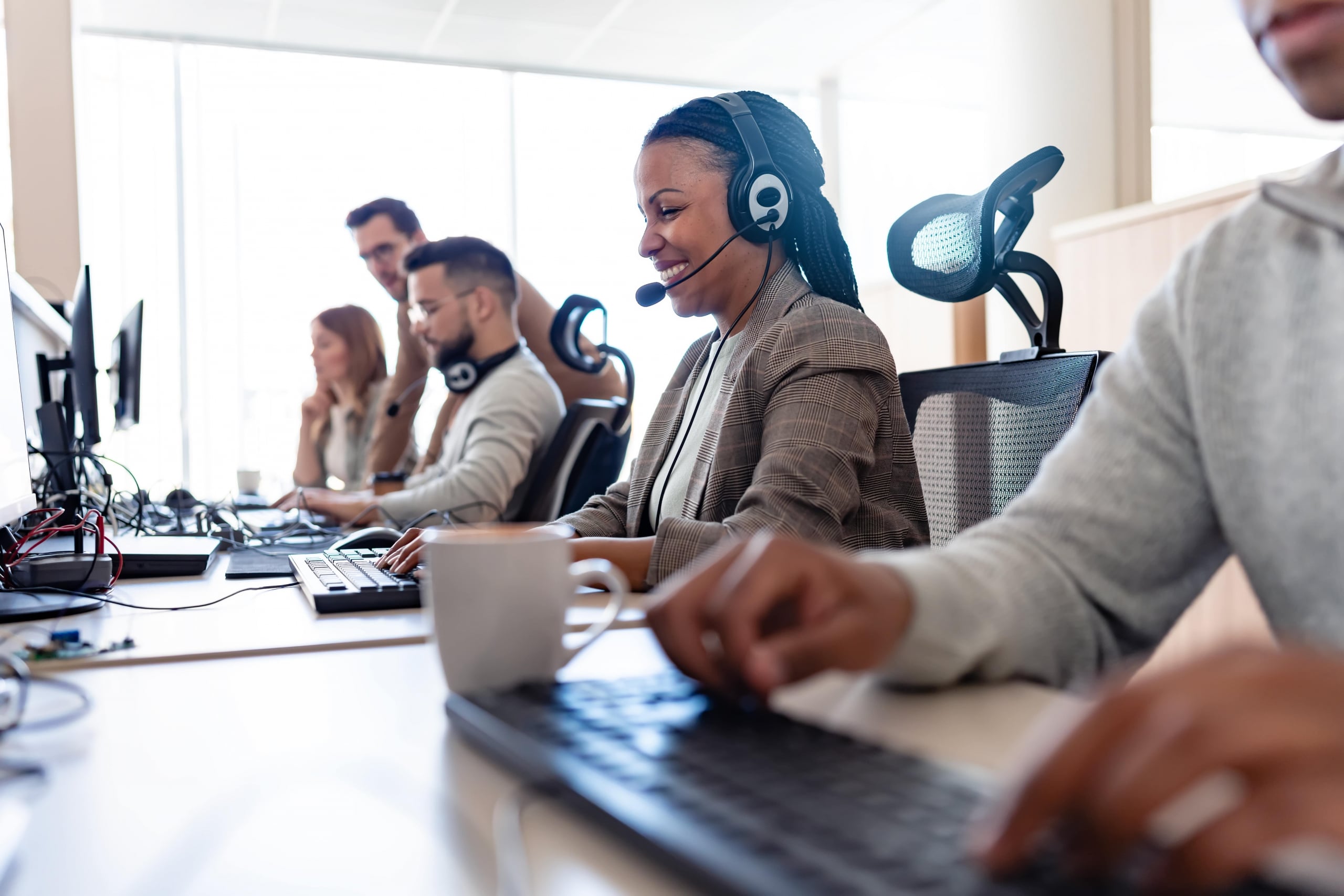 In their office, a multi-ethnic group of IT professionals works together, collaborating and using computers to accomplish their tasks