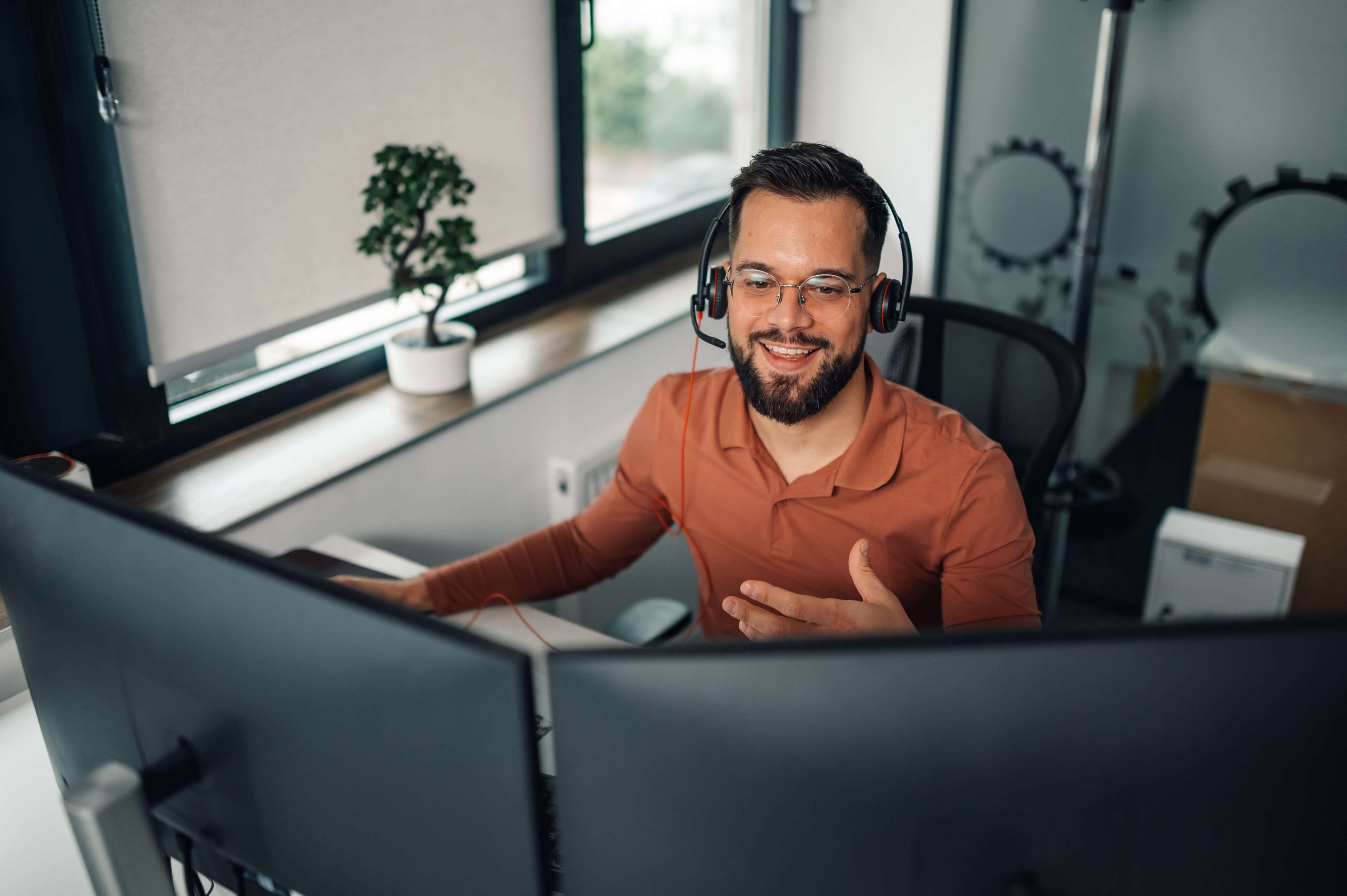 5. Young bearded man with headset on at his computer smiling