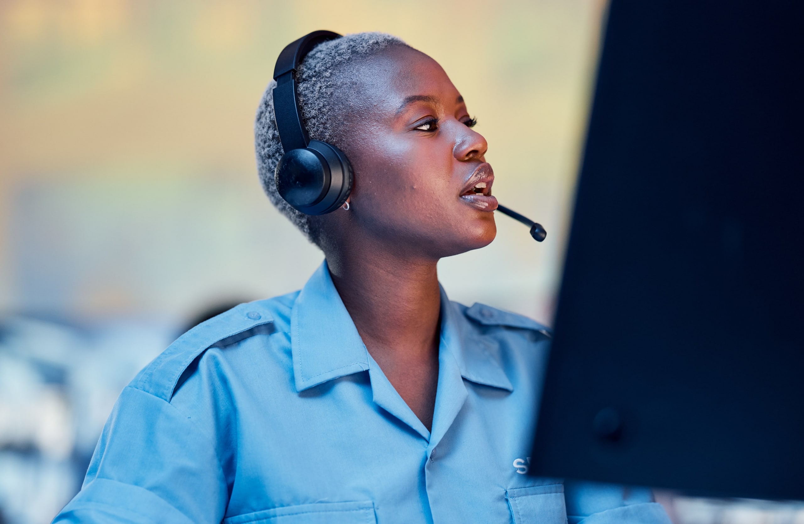 African american woman call center worker with headset talking and looking at her computer