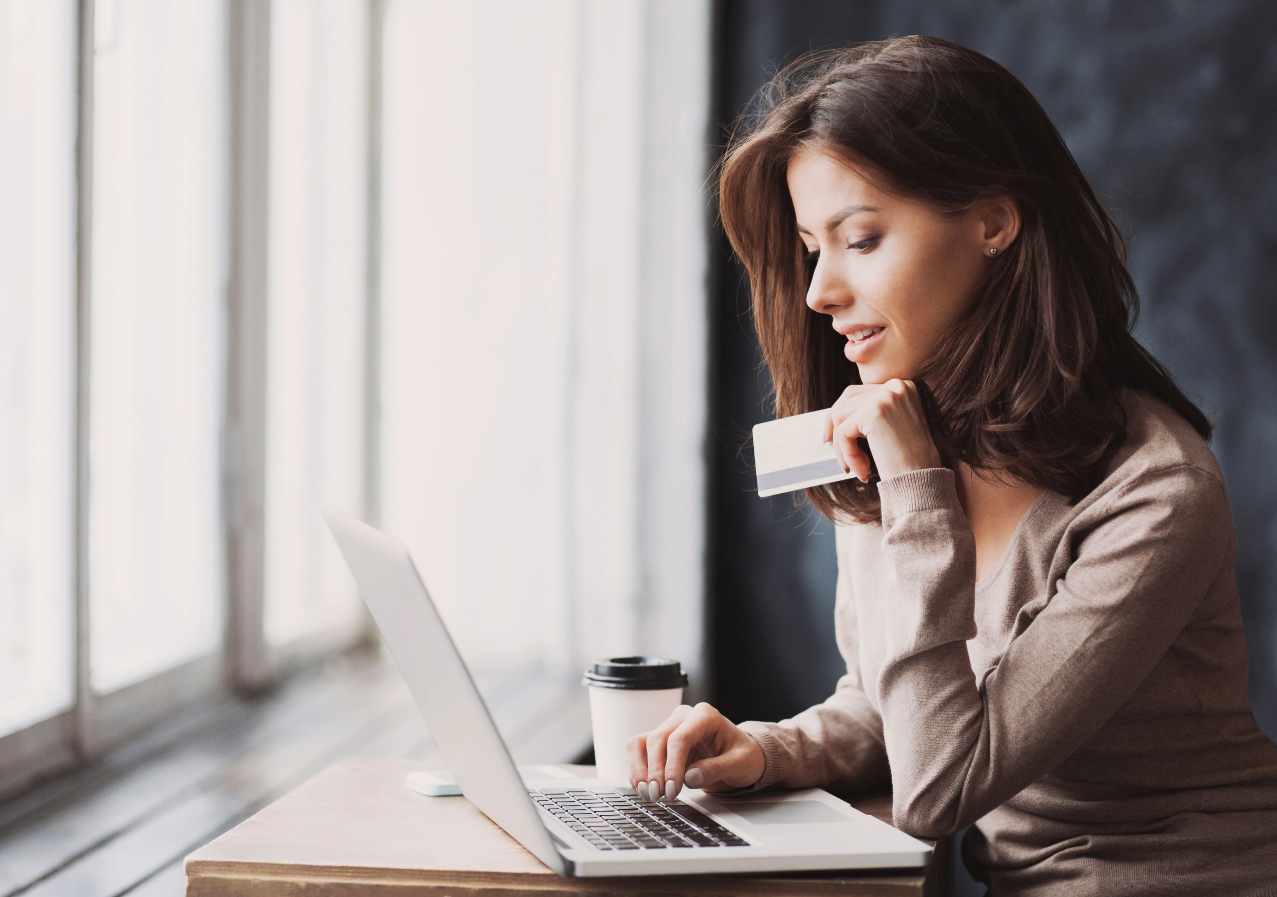 Woman sitting at her laptop holding a credit card