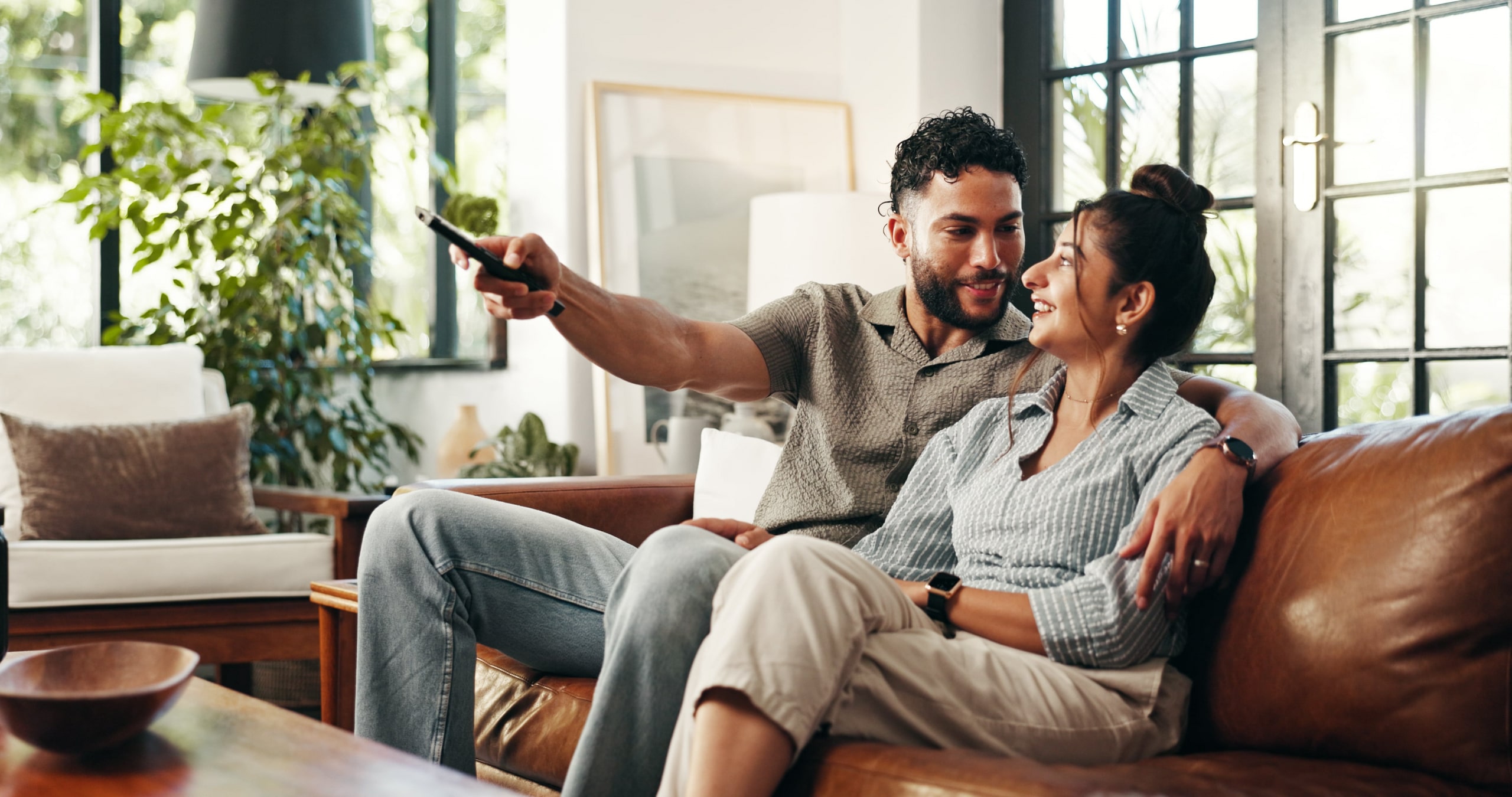 A man and woman on a couch holding a remote deciding what to watch
