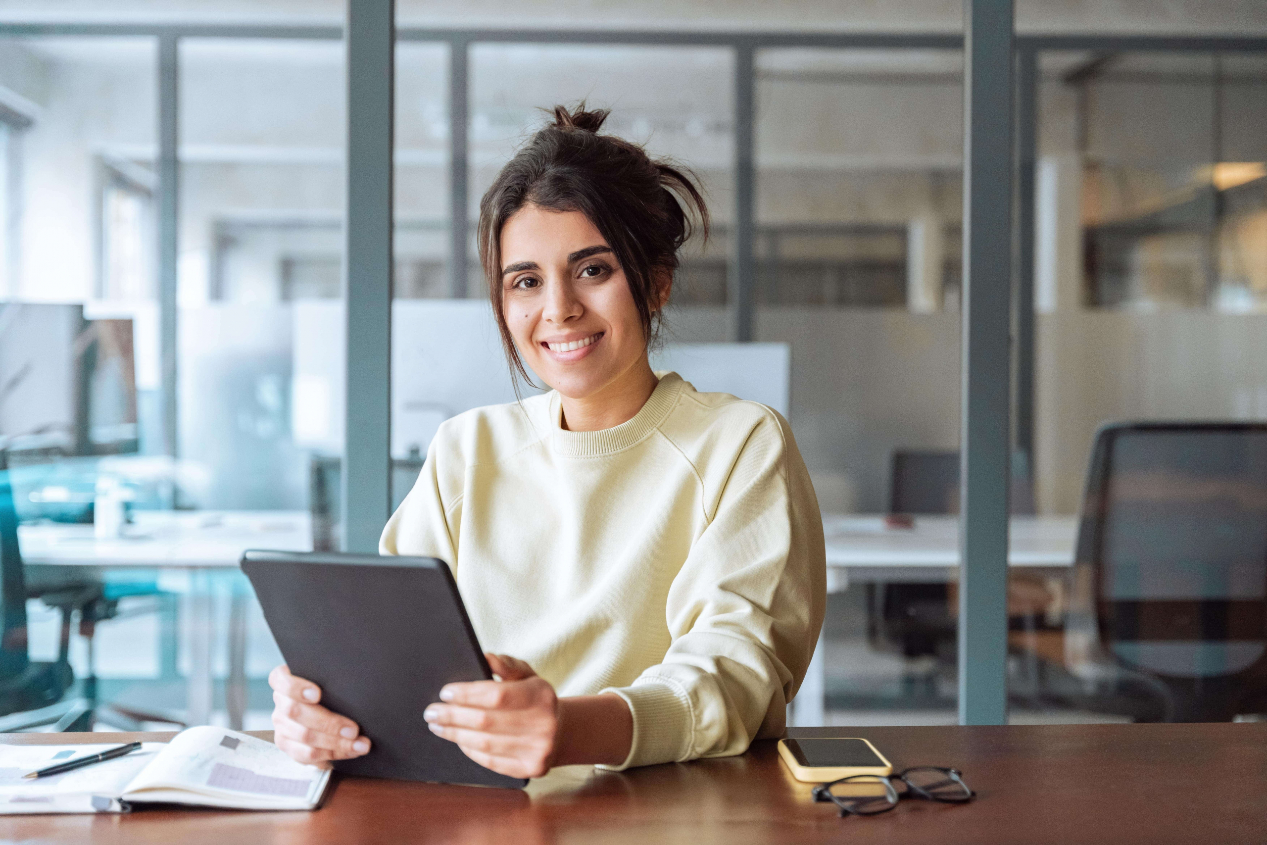 Portrait of middle eastern student or worker using tablet pc financial application standing in office. Smiling indian or latin hispanic business woman holding digital pad computer, looking at camera.