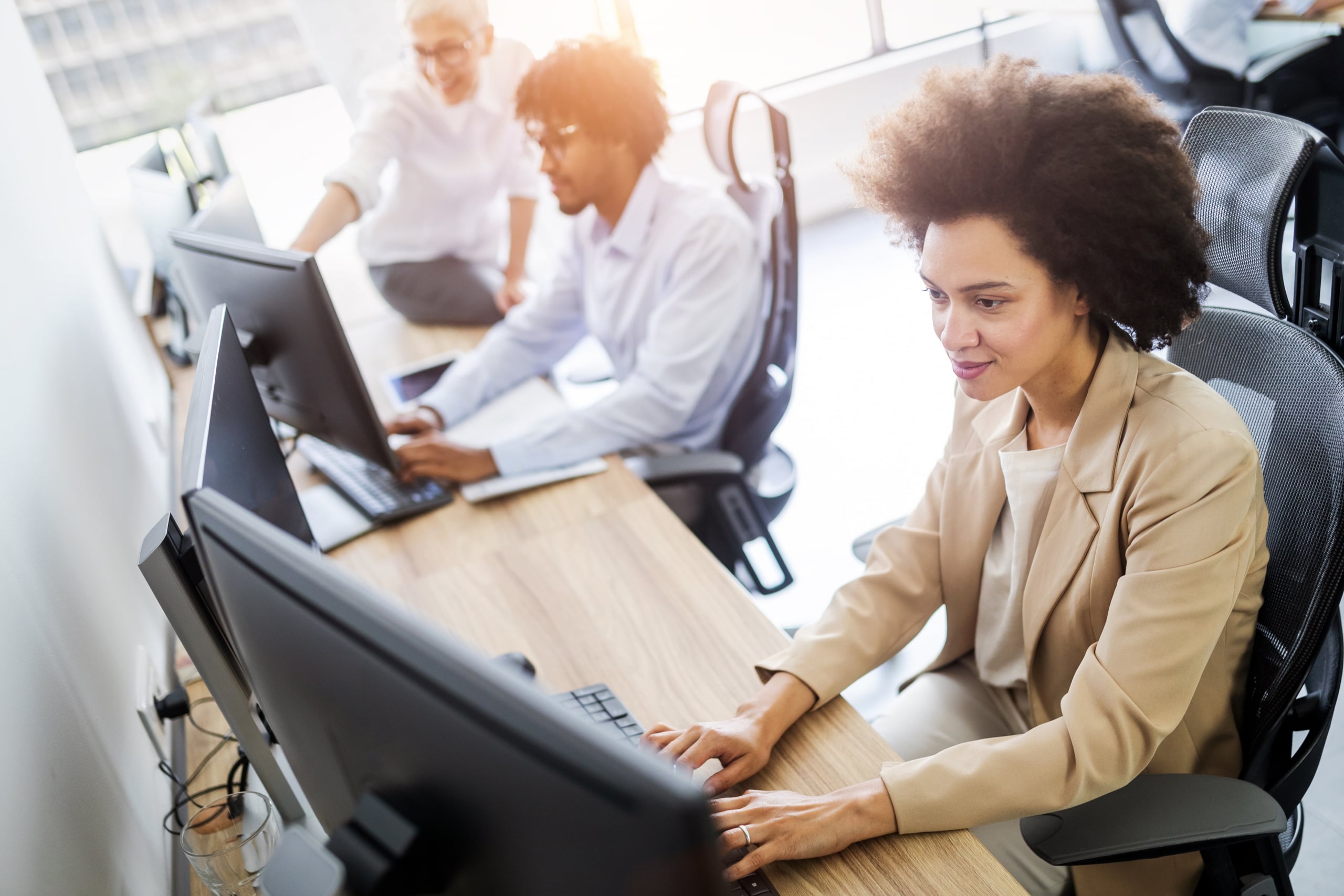 Two co workers sitting at their computers typing