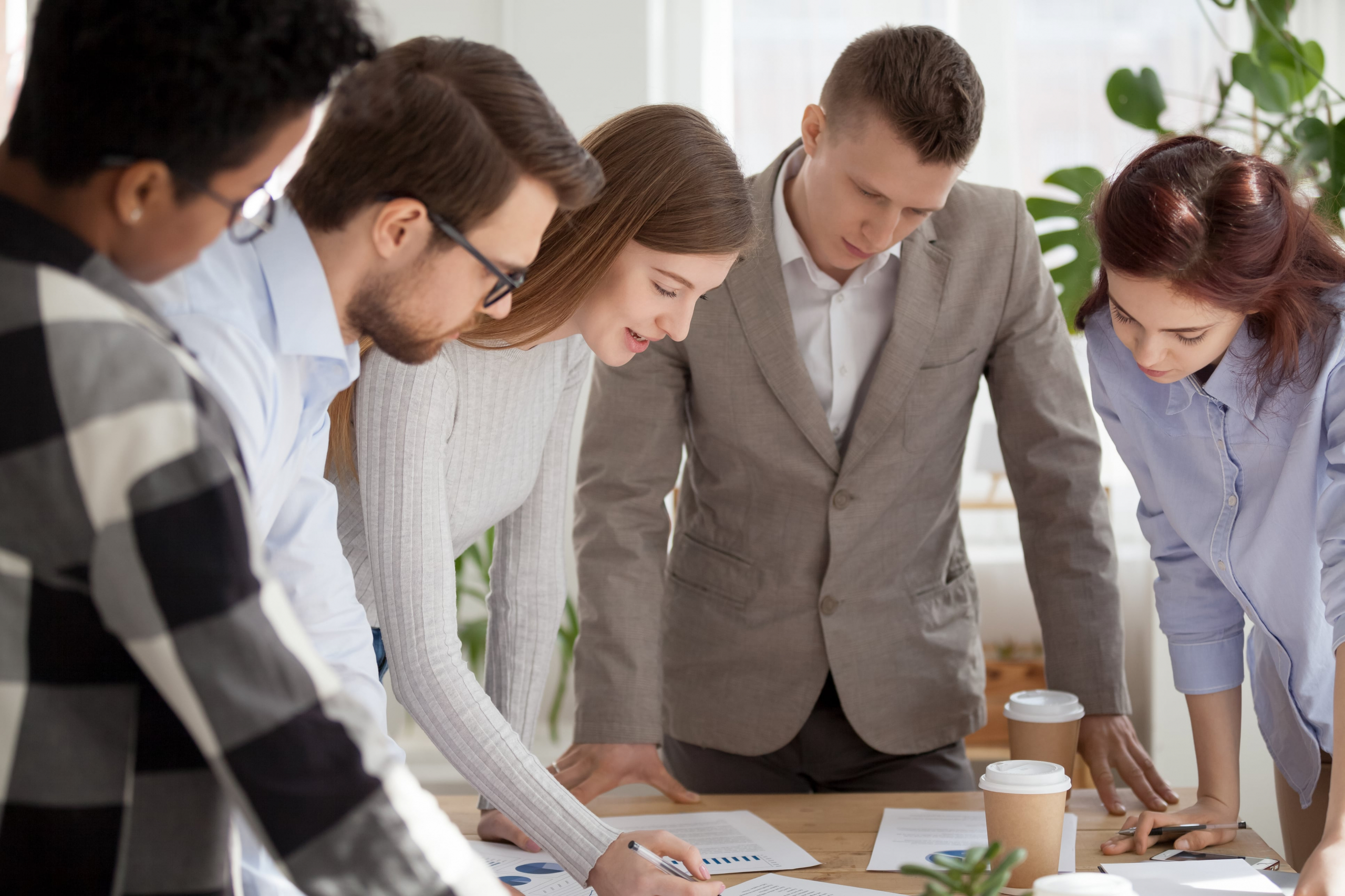 group of co-workers brainstorming while standing and looking at charts and surveys